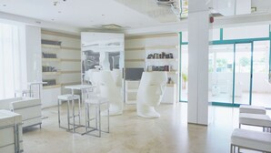 A modern interior with white furniture, a central sculptural installation, and a glass door leading outside. - Beautiful apartment for 5 people with pool, A/C, WIFI, TV, patio and pets allowed (San Salvo)