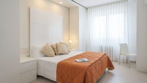 A modern bedroom with a large bed, bedside tables, a chair, and a window with sheer curtains. - Beautiful apartment for 5 people with pool, A/C, WIFI, TV, patio and pets allowed (San Salvo)