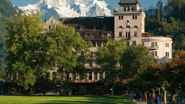 Een hotel met een toren en een berg op de achtergrond.