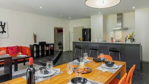 A modern dining area with a wooden table set for four, surrounded by orange chairs. - Beautiful apartment for 4 people with WIFI, TV, balcony and panoramic view (Interlaken)
