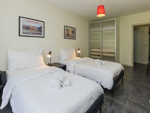Habitación de hotel con dos camas, un armario y una lámpara colgante roja.