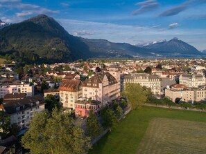 A town with historic buildings, a large open field, and mountains in the background.