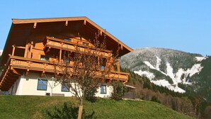 A wooden chalet with balconies, set against a mountainous backdrop. - Stunning  villa for 5 people with WIFI, TV and balcony (Bruck An Der Großglocknerstraße)