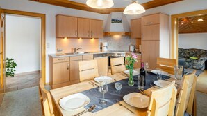 A modern kitchen with wooden cabinets, a dining table set for four, and pendant lighting. - Stunning  villa for 5 people with WIFI, TV and balcony (Bruck An Der Großglocknerstraße)