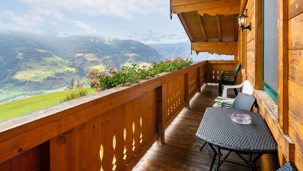 A wooden balcony with a table and chairs, overlooking a mountainous landscape. - Stunning  villa for 5 people with WIFI, TV and balcony (Bruck An Der Großglocknerstraße)