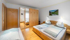 A bedroom with two beds, wooden flooring, a wardrobe, and a painting on the wall. - Stunning  villa for 5 people with WIFI, TV and balcony (Bruck An Der Großglocknerstraße)