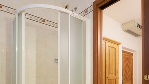 A bathroom with a glass shower enclosure, wooden cabinets, and a tiled floor. - Hotel La Rosa (Borgo San Lorenzo)