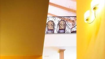 Eine Treppe mit Handlauf, eine Tür am unteren Ende und ein Balkon mit Geländer.