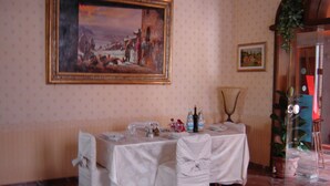 A dining area with a table set for four, a painting on the wall, and a potted plant. - Hotel La Rosa (Borgo San Lorenzo)