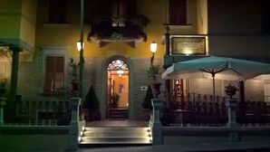 A building entrance with a staircase leading up to a door, two wall-mounted lights, and a sign above the door. - Hotel La Rosa (Borgo San Lorenzo)