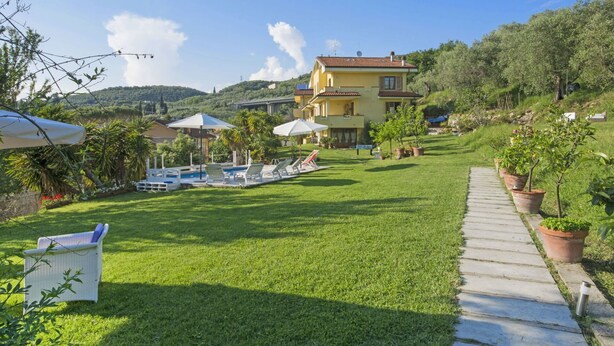 Une villa dotée d’une piscine, d’un espace salon extérieur et d’un chemin qui traverse le jardin.