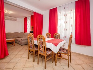 Uma área de refeições com uma mesa redonda, seis cadeiras e cortinas vermelhas.