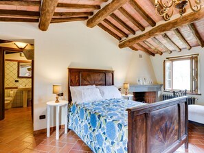 A bedroom with a wooden bed, a fireplace, and a window with a view. - Beautiful  villa for 8 people with private pool, WIFI, TV, balcony, pets allowed and panoramic v... (Pescia)