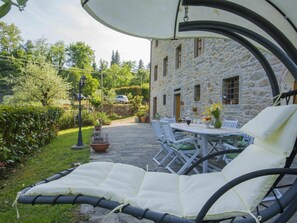 A stone building with a patio area featuring a table and chairs, a hanging chair, and a garden with a lamp post. - Stunning  villa for 8 people with private pool, WIFI, TV, balcony, pets allowed and panoramic view (Pescia)