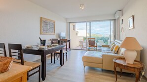 A spacious living area with a dining table, chairs, a sofa, and a TV.