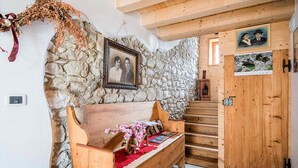 A rustic interior with a stone wall, wooden bench, and a staircase leading to a door with a picture above it. - Cosy apartment for 2 guests with WIFI, TV, patio and pets allowed (Barcis)