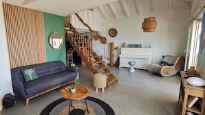 A living room with a sofa, a coffee table, a staircase, and a view of the outdoors. - VILLA PINEL BAY VIEW - Sea and St Barth view villa with pool and sea access (ST MARTIN)