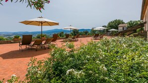 A patio with outdoor seating, umbrellas, and a view of the countryside. - Nice apartment in villa for 2 guests with WIFI, A/C, pool, patio and panoramic view (Cinigiano)