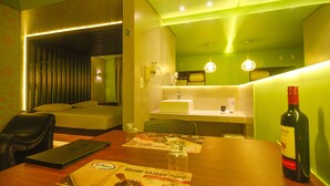 A hotel room with a bed, a desk with a laptop, a bottle of wine, and a menu on the table. - Classe A Motel (São Paulo)