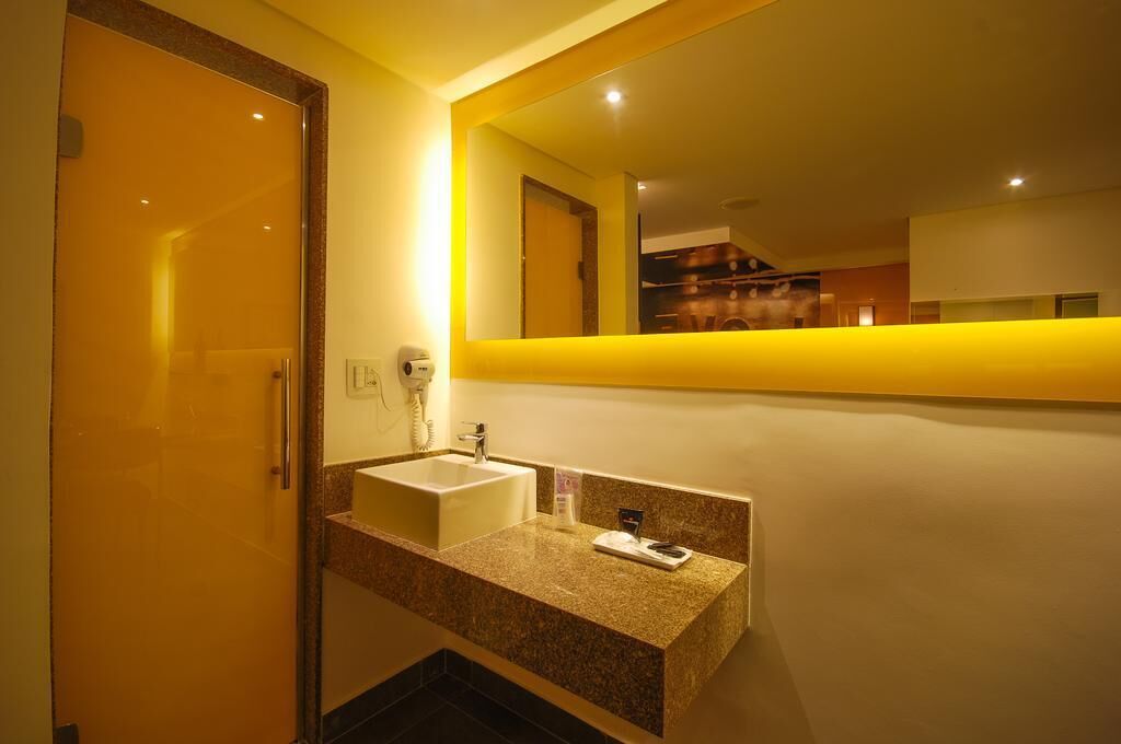 Une salle de bain d’hôtel avec un lavabo, un miroir et une porte.