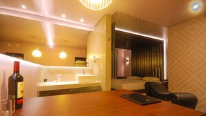A hotel room with a wooden dining table, a bottle of wine, and a laptop. - Classe A Motel (São Paulo)