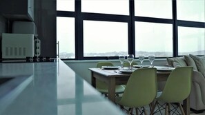 Un espace de restauration moderne, doté d’une longue table, de chaises et offrant une vue dégagée grâce à de grandes fenêtres.