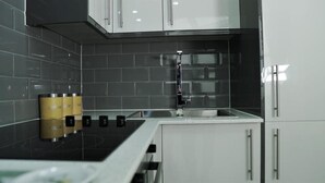 Een moderne keuken met een zwart betegelde spatwand, roestvrijstalen apparatuur en witte keukenkastjes.