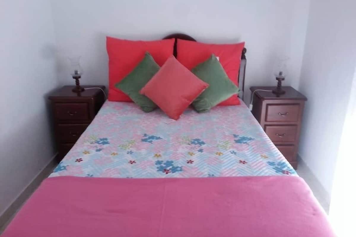A bed with a floral bedspread, two nightstands, and a headboard.