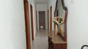 A hallway with wooden doors, a mirror, and a vase with flowers. - Apartamentos Odeceixe (Aljezur)