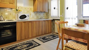 Une cuisine compacte dotée de meubles en bois, d’un four à micro-ondes et d’une cuisinière. Un coin repas avec une table et des chaises est également disponible.