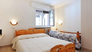 Une chambre avec deux lits, une fenêtre et des lampes fixées au mur.