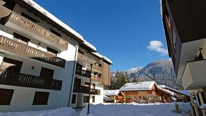 Un bâtiment enneigé, doté de balcons, avec une montagne en arrière-plan.