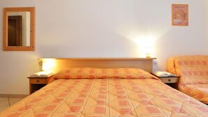 Een hotelkamer met een bed, nachtkastjes, een spiegel en een wandlamp.