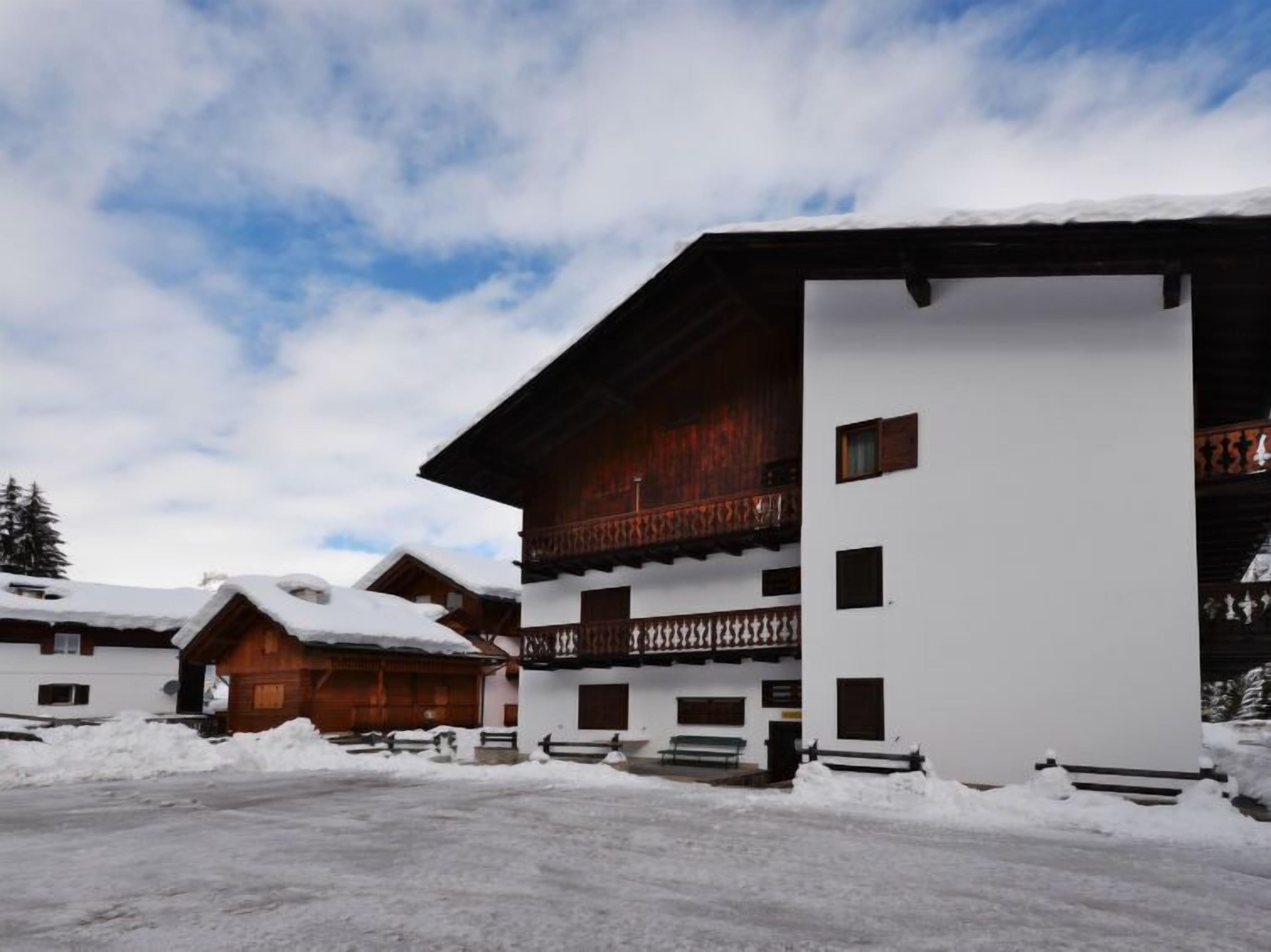 A multi-story building with wooden balconies, surrounded by snow-covered ground.
