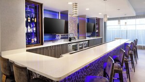 Een moderne bar met een lange toonbank, barstoelen en een wijnkoeler.