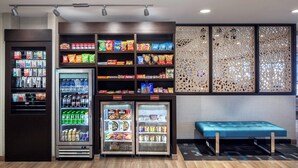 Een snackbar met gekoelde drankautomaten en schappen vol snacks en dranken.