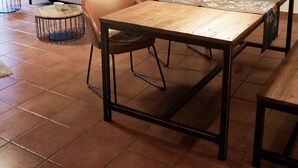 Un coin repas avec une table en bois, des chaises et un mur vert en arrière-plan.