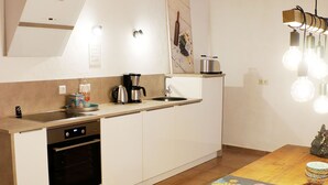 Une cuisine moderne avec des meubles blancs, une table à manger en bois et une machine à café.
