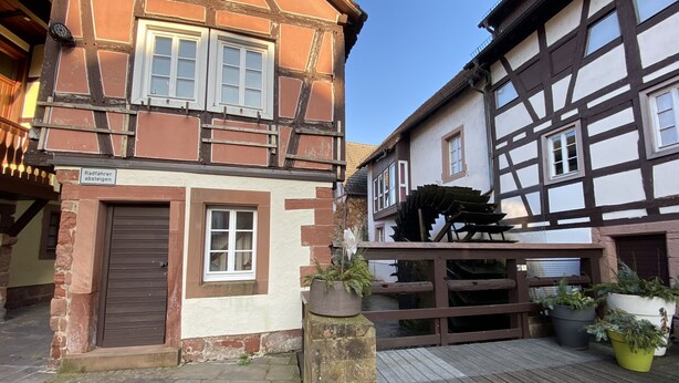 Un bâtiment traditionnel à colombages, sur lequel on peut lire l’inscription : « Les cyclistes doivent descendre de leur vélo ».
