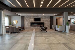 Una sala de estar moderna con chimenea, zona de estar y televisor de pantalla plana en la pared.