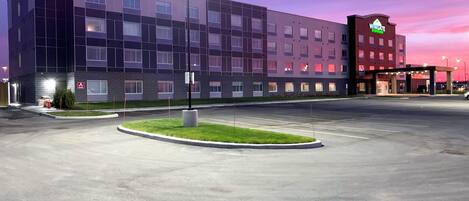 Un hotel moderno con aparcamiento y zonas ajardinadas.
