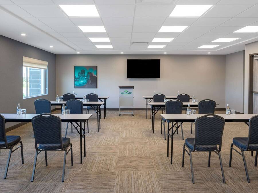 A conference room with a large screen, a podium, and multiple tables with chairs.