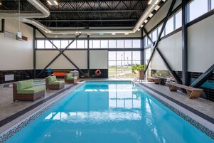 Una piscina interior con sillas de descanso y vistas al exterior.