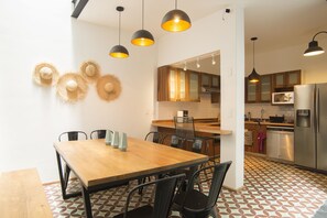 A modern kitchen with wooden cabinets, a stainless steel refrigerator, and a dining area with a wooden table and chairs.