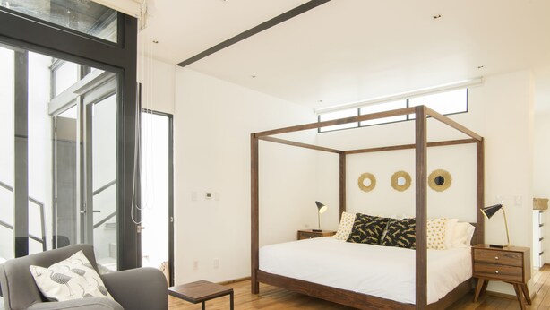 A modern bedroom with a four-poster bed, a grey sofa, and a small table. - Central Luxury house - Condesa Neighborhood (Colonia Condesa)