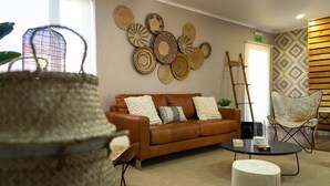 A modern living room with a brown leather sofa, a round coffee table, and a patterned wall. - Hotel Boutique Restaurant Kran Kreen (Punta Arenas)