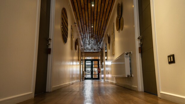 A hallway with wooden floors and a ceiling with wooden beams. There are doors at the end of the hallway. - Hotel Boutique Restaurant Kran Kreen (Punta Arenas)