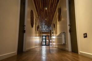 A hallway with wooden floors and a ceiling with wooden beams. There are doors at the end of the hallway. - Hotel Boutique Restaurant Kran Kreen (Punta Arenas)