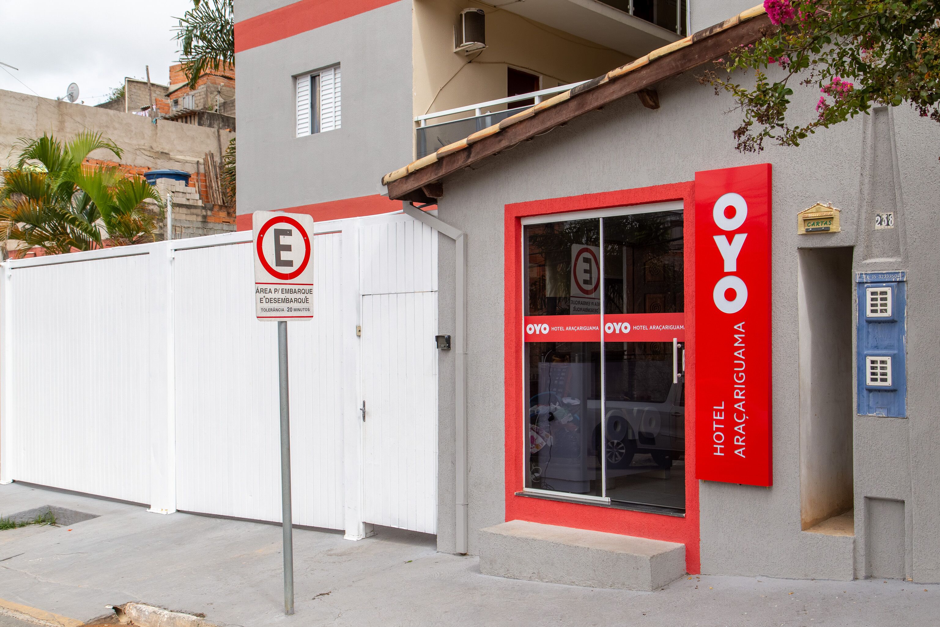 A hotel named OYO with a red and white facade, a closed gate, and a no parking sign.
