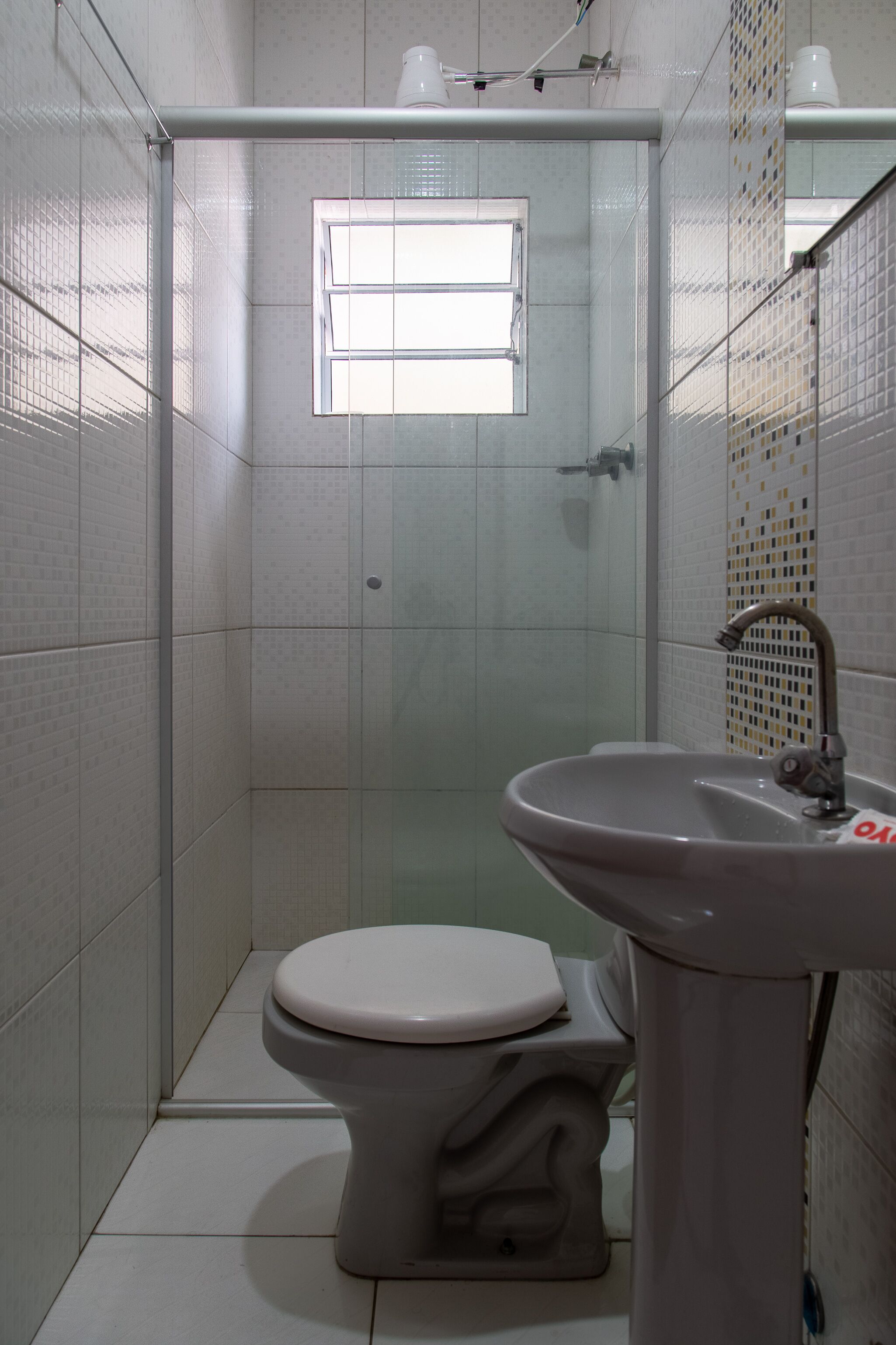 Un baño con inodoro, lavamanos y cabina de ducha con mampara de vidrio.